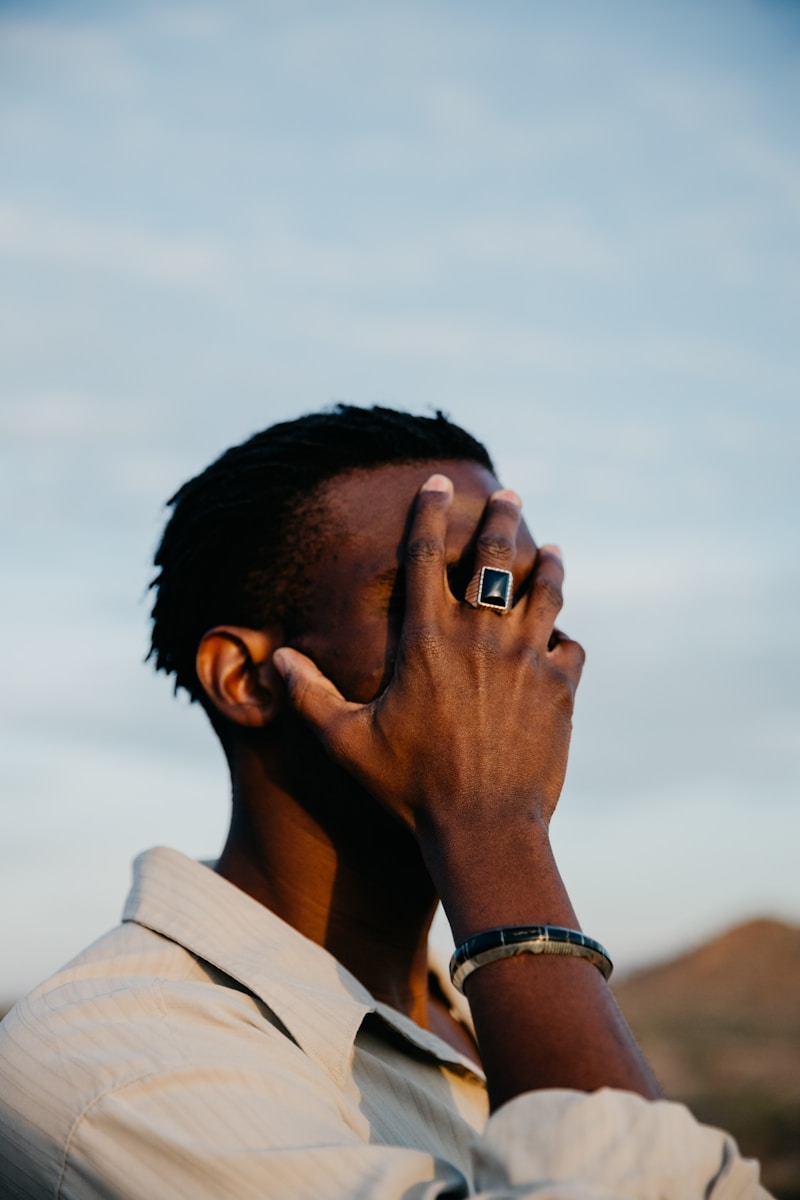 Man covering face with hand, wearing a ring.