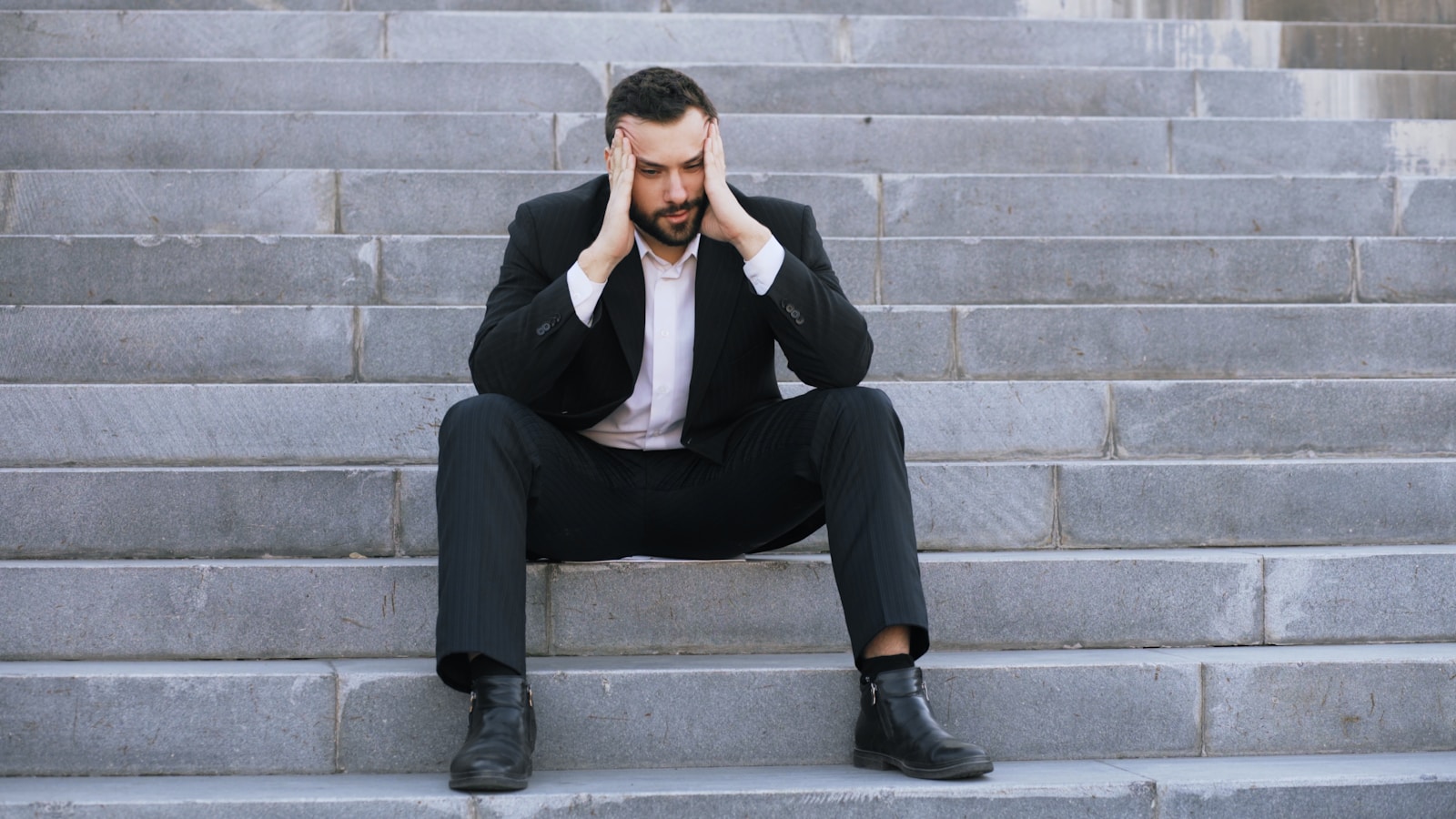 Photo by Vitaly Gariev - Lina Hadid Man in suit sitting on stairs with head in hands